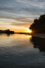 Peaceful sunset scene on the Yasawa Islands, Fiji. Small islands during sunset. Bright sunset sky over dark water. Tiny calm waves in front of the dark hills of a nearby island. Vacation paradise