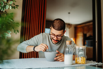 Young caucasian man eating corn flakes for breakfast at home