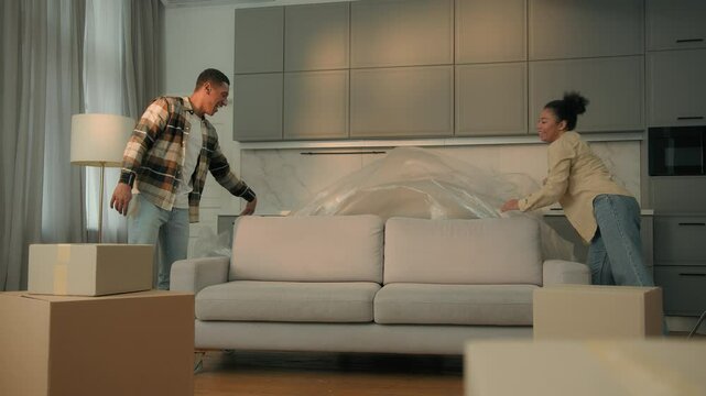 African American man woman happy family home owners tenants moving new house relocation buy rent apartment repair affectionate couple unpacking furniture bonding on couch sofa delivery mortgage credit - Powered by Adobe