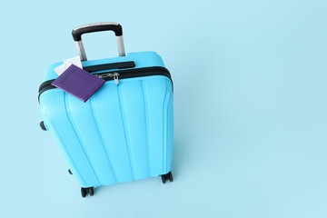 Suitcase with purple passport and tickets on blue background. Travel concept
