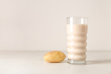 Glass of tasty potato milk on light background