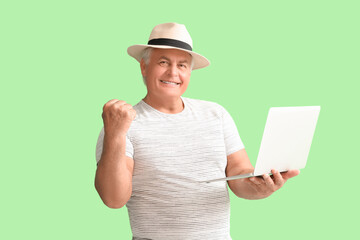 Happy senior man with laptop on green background