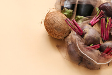 Eco bags with different fresh products on beige background, closeup