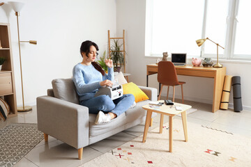Young woman with cash counting machine at home
