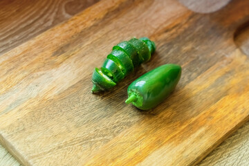 green hot peppers whole and sliced pod, jalapeno fresh on a wooden background