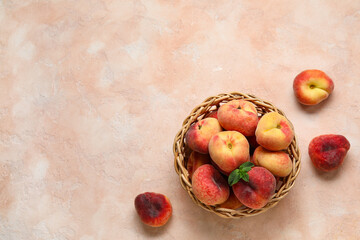 Wicker bowl with sweet fig peaches and mint on pink background