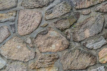 stacked stone wall of uneven cobblestones, old and weathered background