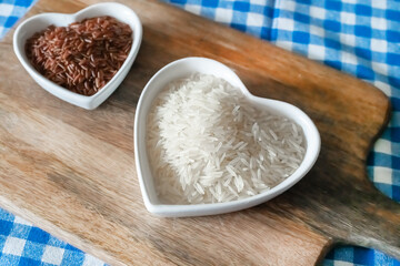 set of red and white rice in a plate in the shape of a heart close-up on a chopping wooden background