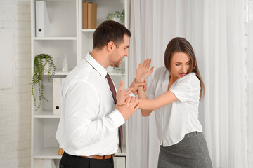 Business man grabbing his female colleague's hands in office. Harassment concept