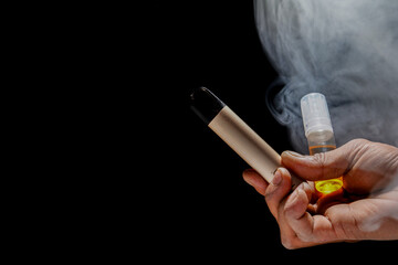 hand holding e-cigarette with refillable liquid on black background for copy space, electronic...