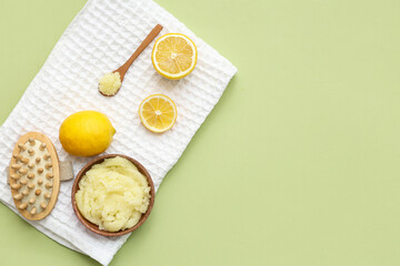 Composition with natural body scrub, massage brush, towel and lemons on green background