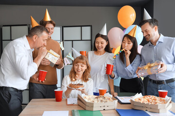Young businesswoman with cake and her colleagues at birthday party in office