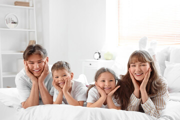 Fototapeta premium Happy parents with their little children lying in bedroom