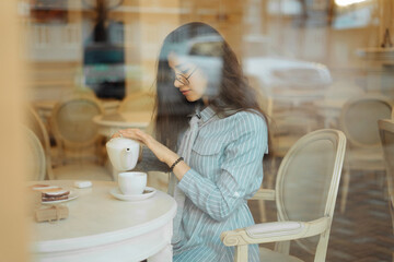 beautiful asian girl enjoying an hot tea in cafe, view through window glass