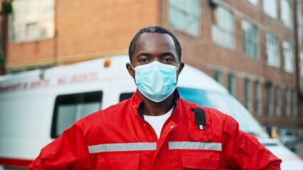 African American senior experienced man paramedic standing outdoor wearing medical mask on face and looking at camera near ambulance vehicle. Close up. Emergency worker. First aid assistance