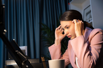 An unhappy sitting businesswoman with stressful feeling's headache and eyestrain for over thinking about waiting job online project sending via e-mail at late night at dark neon workplace. Postulate.