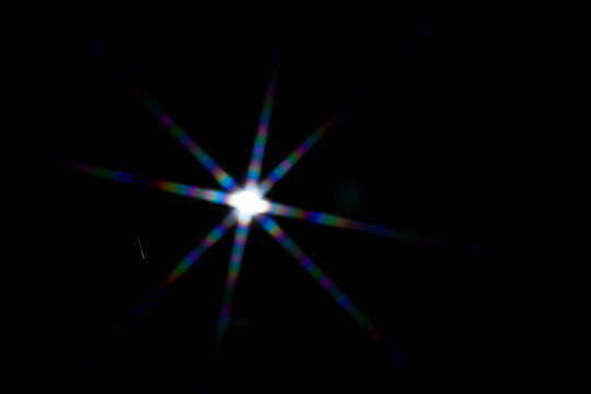 Star shaped lens flare on black background.
