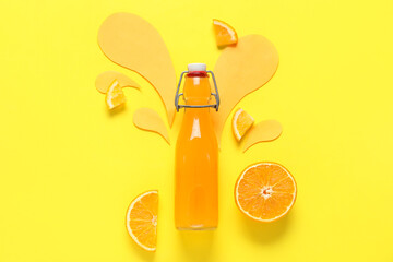 Bottle of fresh orange juice and splashes made of paper on yellow background
