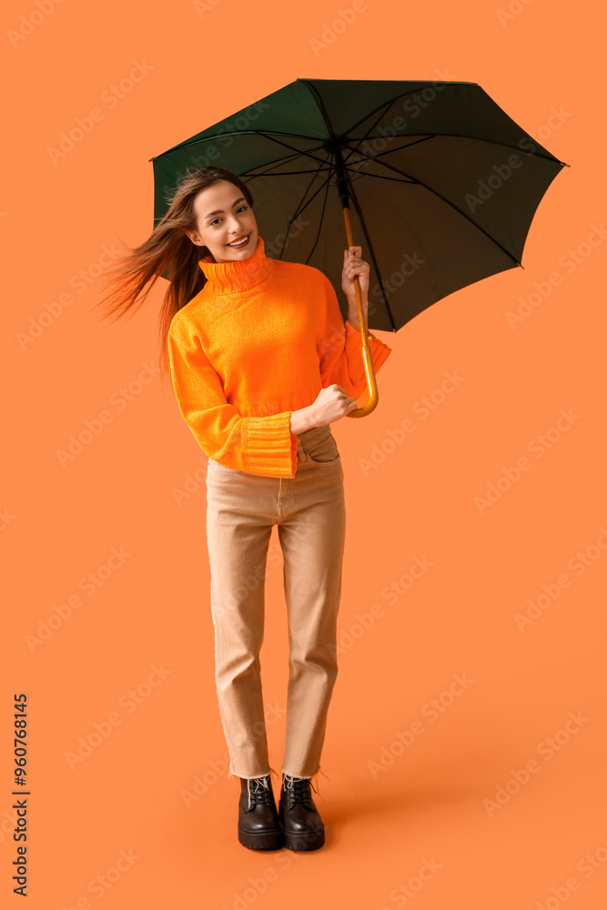 Poster Beautiful young woman with umbrella on orange background