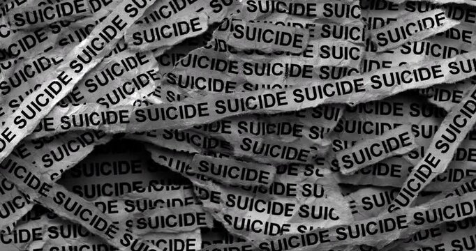 Strips of newspaper with the words Suicide typed on them. Black and white. Close up.