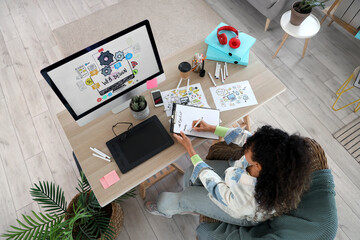 Female African-American web designer writing to-do list at table in office, top view