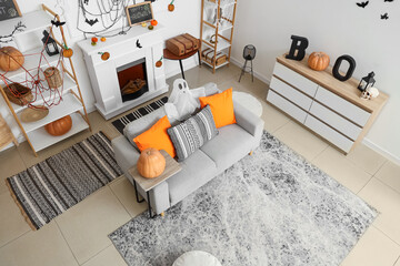 Interior of light living room decorated for Halloween with sofa and shelf units