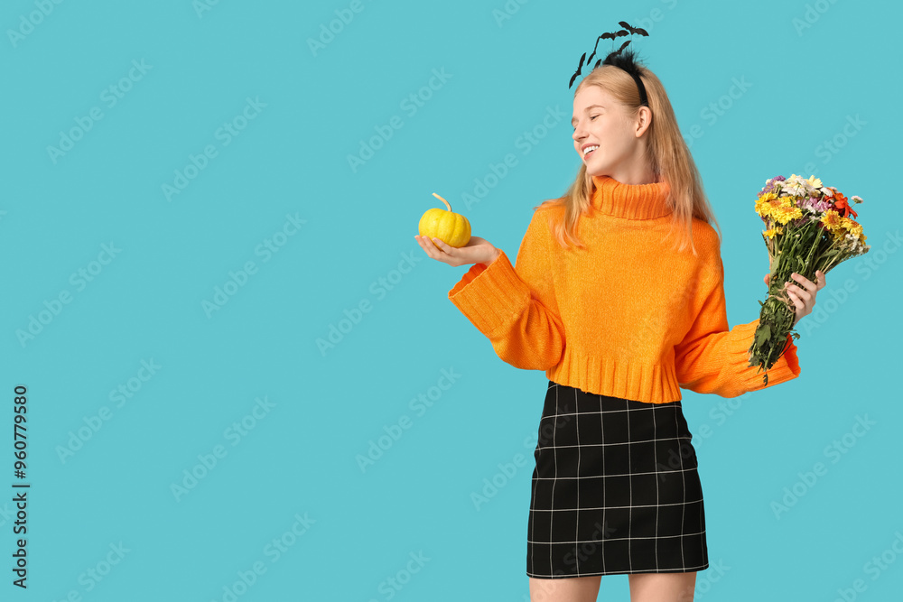 Canvas Prints Beautiful young happy woman in headband with Halloween pumpkin and bouquet of flowers on blue background