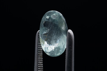Elegant Close-up of a Pristine Faceted Gemstone Held in Precision Tweezers