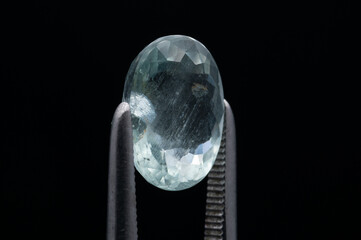 Captivating Aquamarine Gemstone held by Precision Tweezers on a Black Background