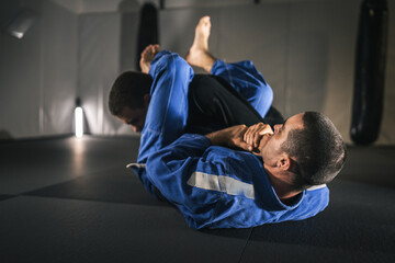 BJJ Brazilian Jiu jitsu Athlete fighters training sparing technique at the academy fight in gi...