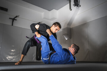 BJJ Brazilian Jiu jitsu Athlete fighters training sparing technique at the academy fight in gi kimono