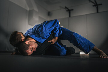 BJJ Brazilian Jiu jitsu Athlete fighters training sparing technique at the academy fight in gi kimono