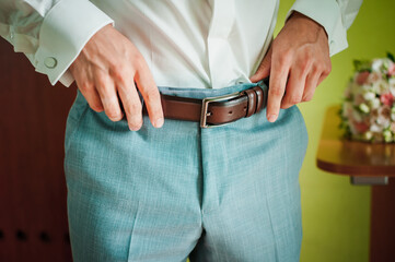 Elegant Groom Adjusting Belt on Wedding Day in Stylish Attire