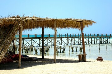 Relaxing Under a Sunshade on Paradise Island With Wooden Pier and Serene Red Sea Backdrop