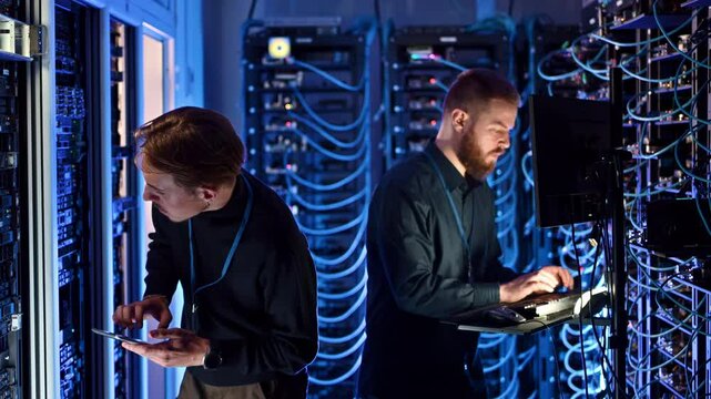 Two men managing data in a server room
