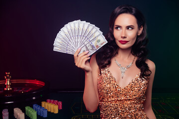 Photo of pretty elegant person hand hold hundred dollar bills casino roulette wheel table isolated on dark background