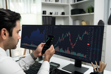 Trader businessman searching on smartphone, analyzing in dynamic stock exchange investment screen on pc with invest highest profitable financial technology market at modern home office. Surmise.