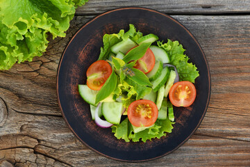 Plate with diet salad on old wooden background, top view