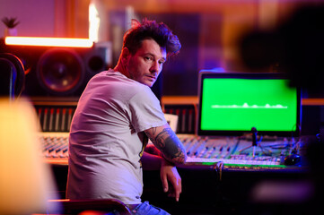 Music producer and sound engineer adjusting levels on a soundboard in a studio