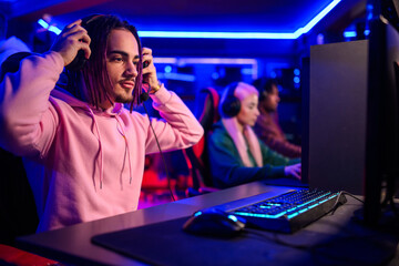 Teenage gamer putting headset and preparing for game play in cybercafe