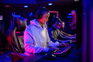 Fototapeta premium Gamer girl with headset sitting in cybercafe and playing video games.