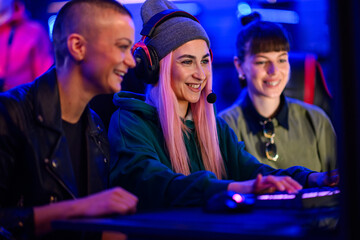 Gamer girl sitting in cybercafe with her friends and playing mmo rpg.