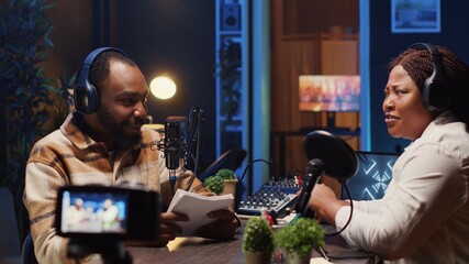 Internet show host making woman laugh, cracking jokes during comedy focused podcast filmed with professional gear. Talking show interviewer broadcasting live from studio with recording camera