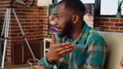 Close up on african american man telling entertaining story to women at apartment party during weekend gathering. Group of friends listening to funny tale from host in living room, zoom in shot