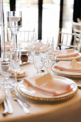 Beautifully set table with plates and clear glasses in a restaurant. Guest table in a restaurant. Vertical photo of a reserved table in a cafe or restaurant