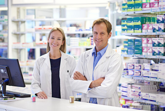 Pharmacy, man and woman in portrait with smile, confidence and prescription drugs in clinic. Teamwork, advice and pharmacist with arms crossed, medicine and pills for medical service at counter