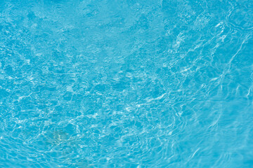 Blue water with ripples on the surface. Defocus blurred transparent blue colored clear calm water surface texture with splashes and bubbles. Water waves with shining pattern texture background.