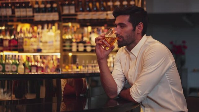 Smart man in white shirt drinking cocktail Old fashioned of special party beverage vibrant waiting for friends or couple at nightclub on Friday meeting night time at luxurious counter bar. Vinosity.