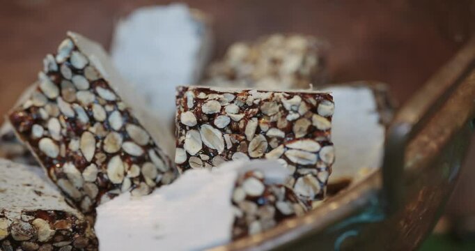 A bowl of pistachio halva with nuts and raisins scattered throughout the bowl