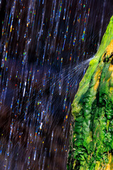 Water falling from the natural bridge bounces off of a mossy travertine formation creating a splash...